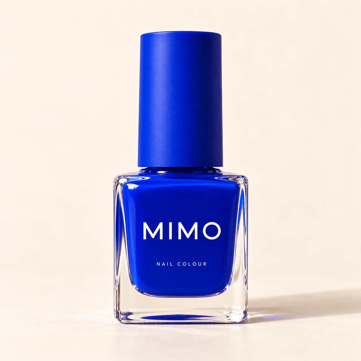 สีทาเล็บ MIMO สีน้ำเงินโคบอลต์ ขวดแก้วทรงเหลี่ยม ฝาสีเดียวกัน บนพื้นสีครีม